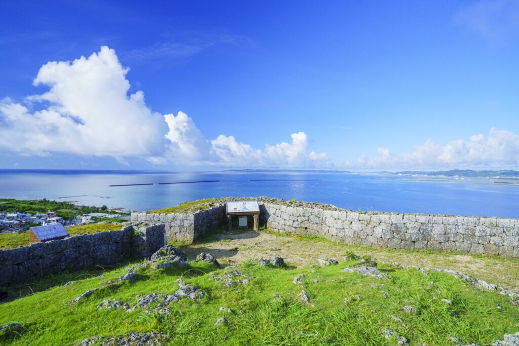 勝連城跡（一の曲輪）の石垣から、広大な青い海と空、遠く島々を見下ろすパノラマビュー。